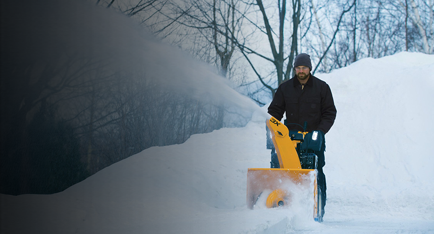 A man pushing a snow blower through heavy snow with the text, snow blower guide, learn how to pick the right one. Read more.